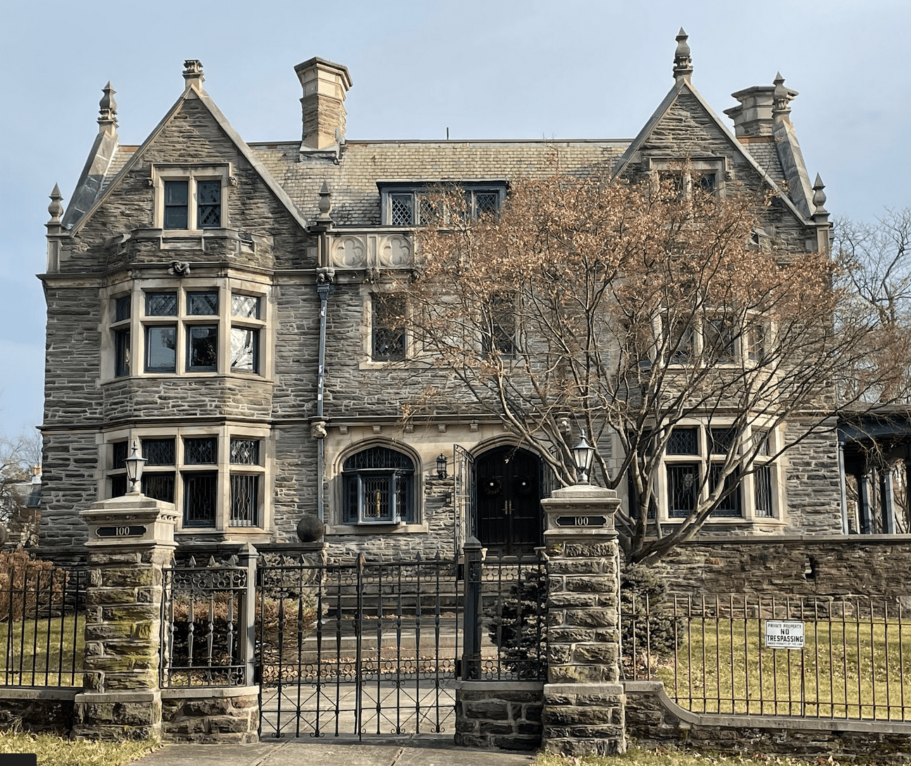 Large Jacobean Revival three-story stone house with multiple bay windows.